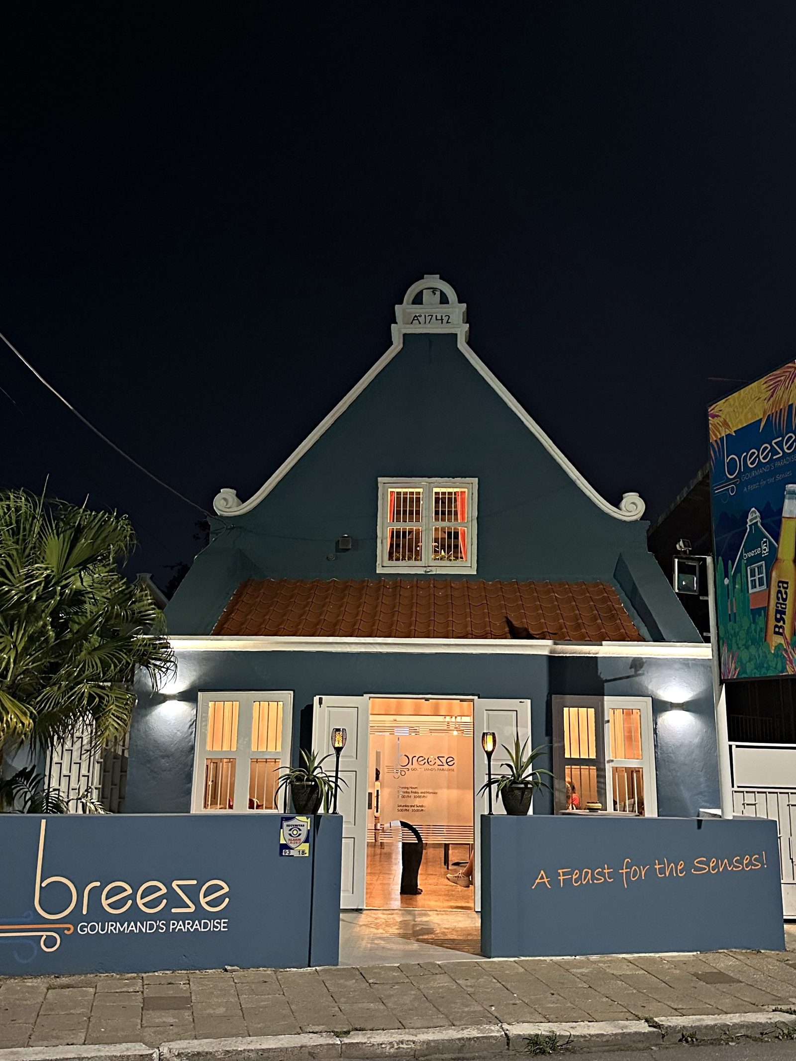 A green gabled building lit at night in Willemstad