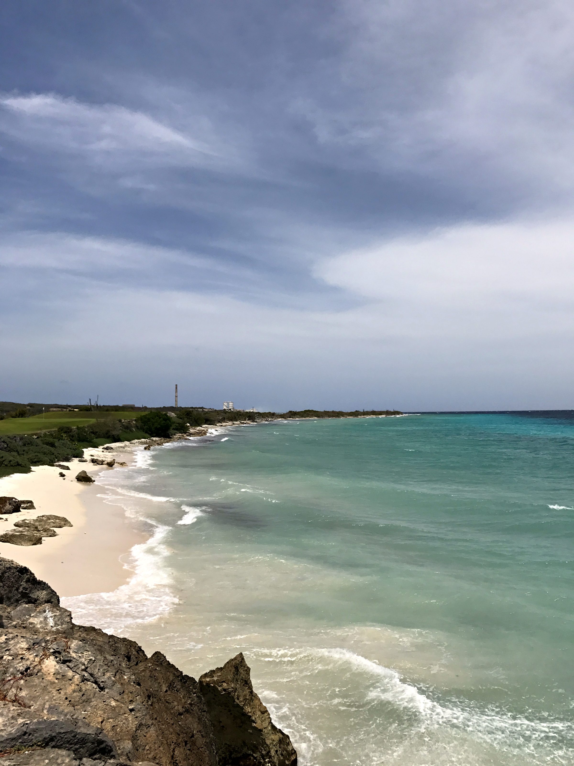 Sandy coastline with turquoise water and breaking waves under a blue sky