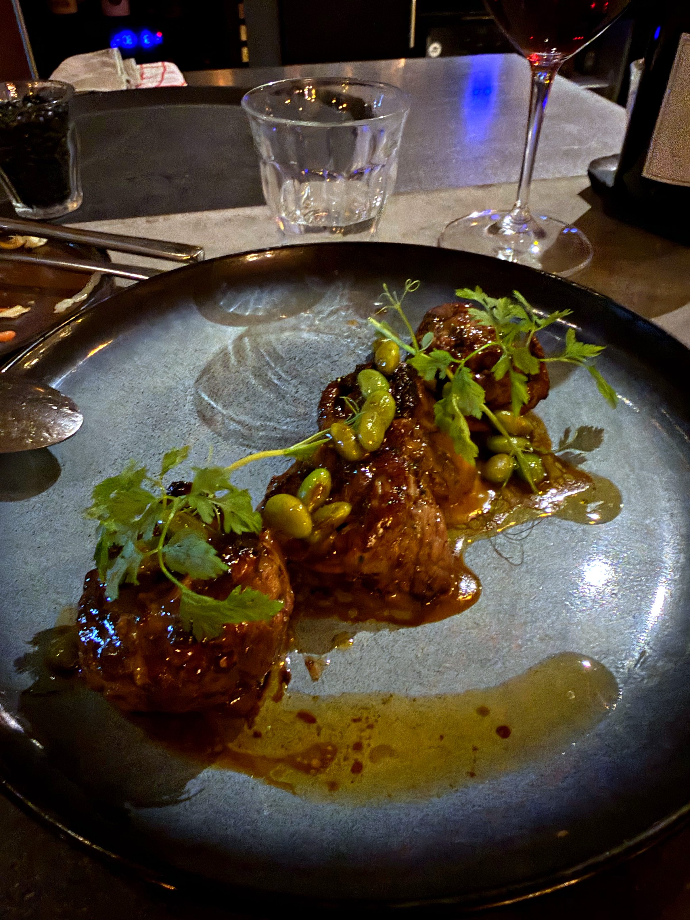 Flank steak rolls with garnish on a dark plate at BKLYN