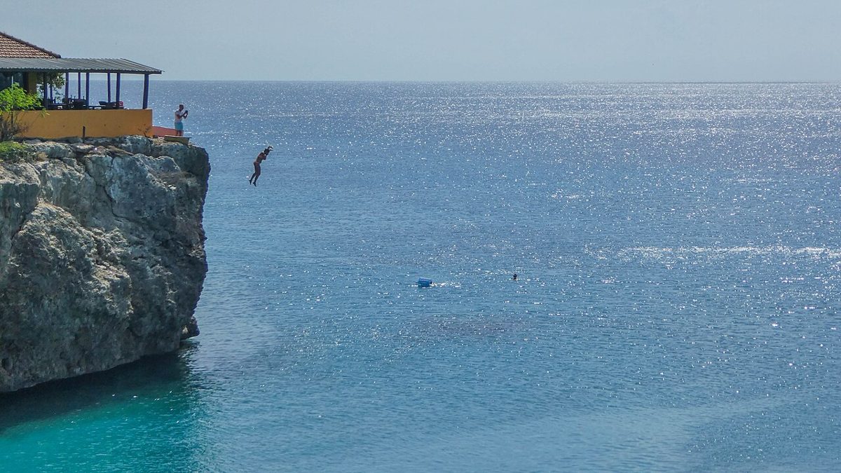 A person jumping from the cliff at Playa Forti, Curaçao