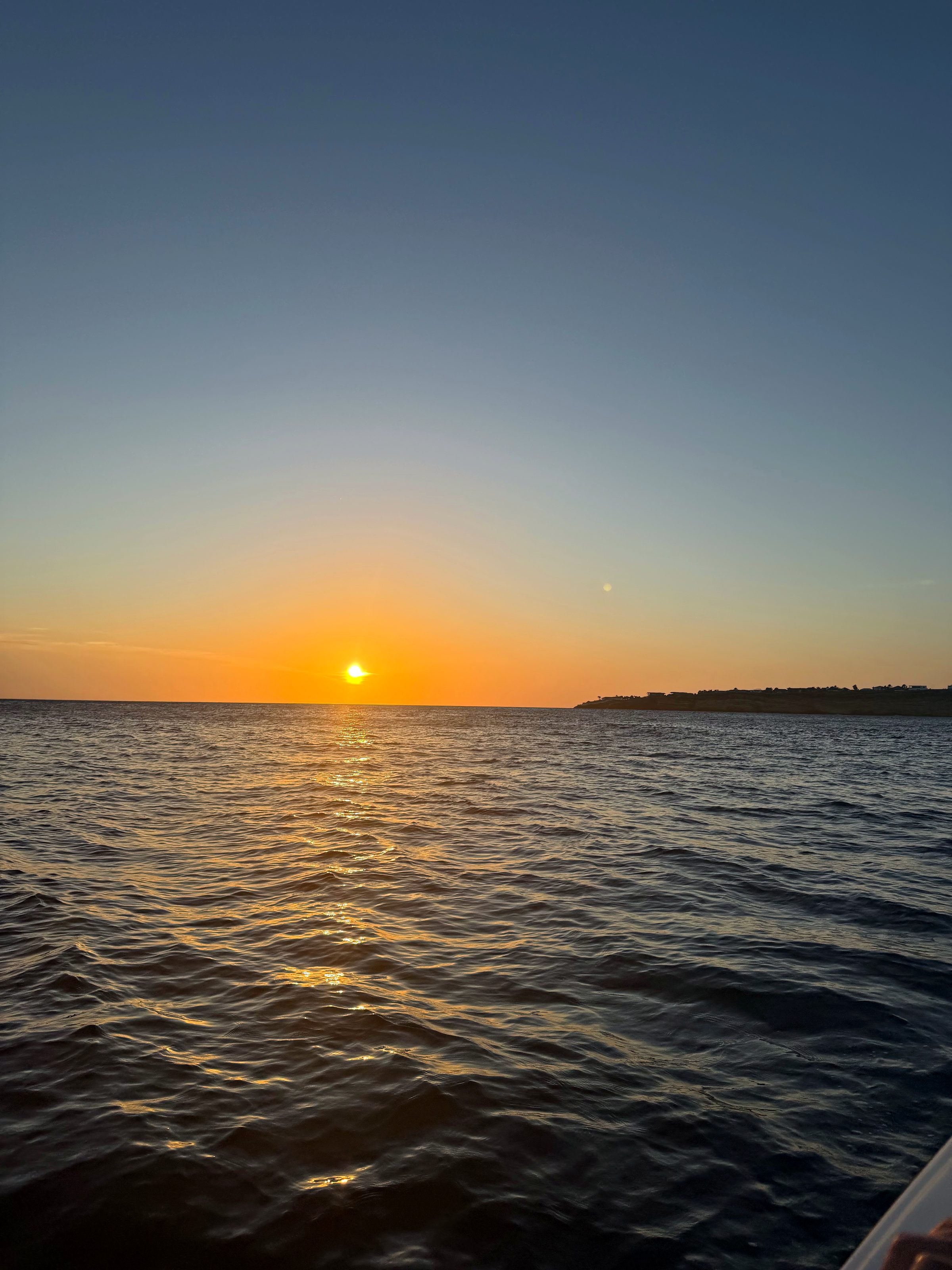 The sun setting on the horizon seen from a boat on open water