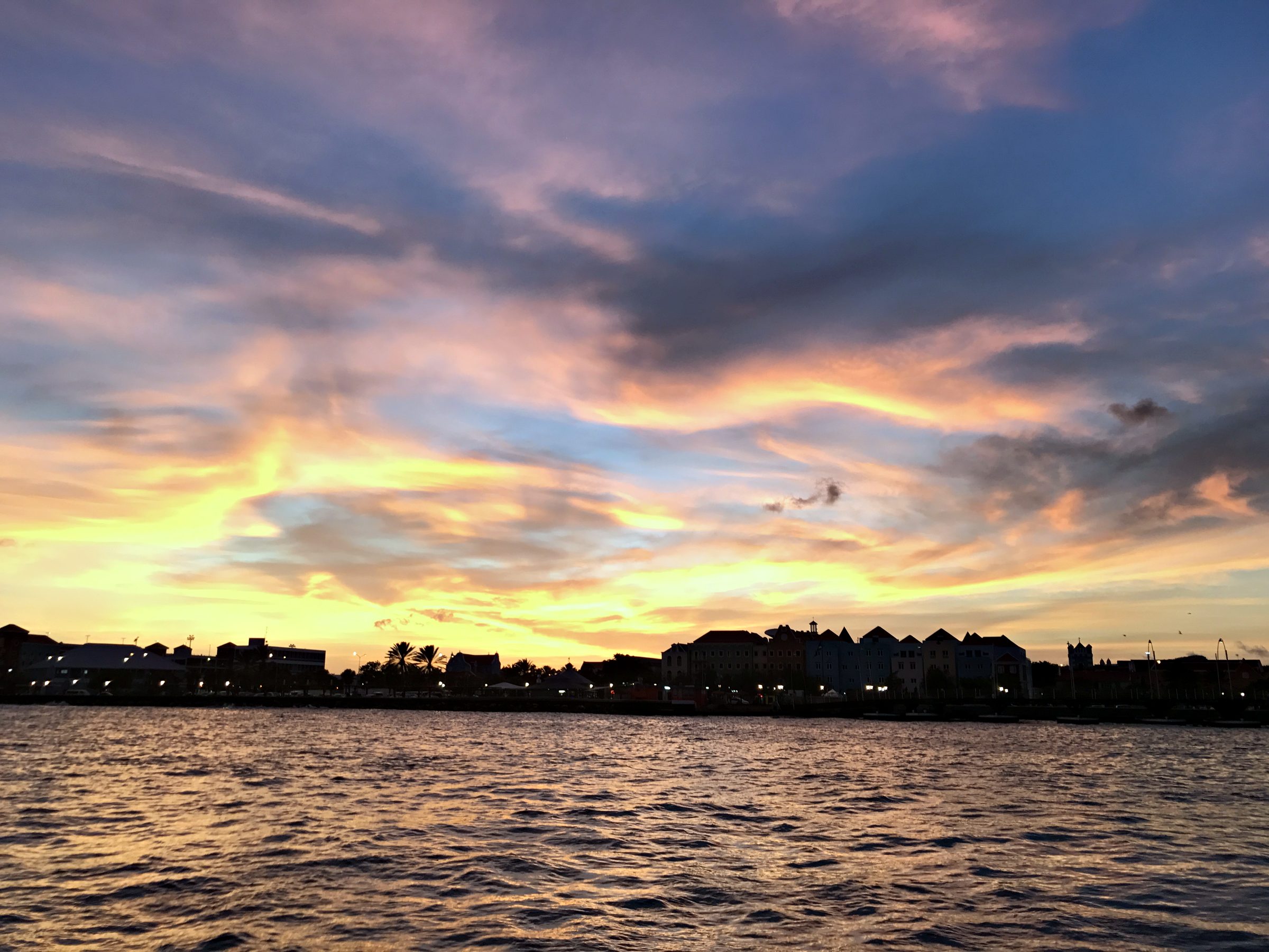 Pink and orange sunset over calm water and a distant shoreline