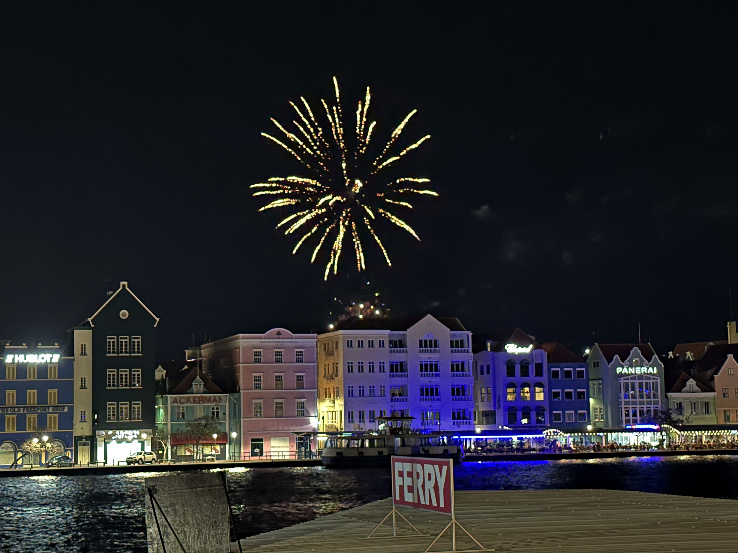 Fireworks over the illuminated Handelskade waterfront in Willemstad at night