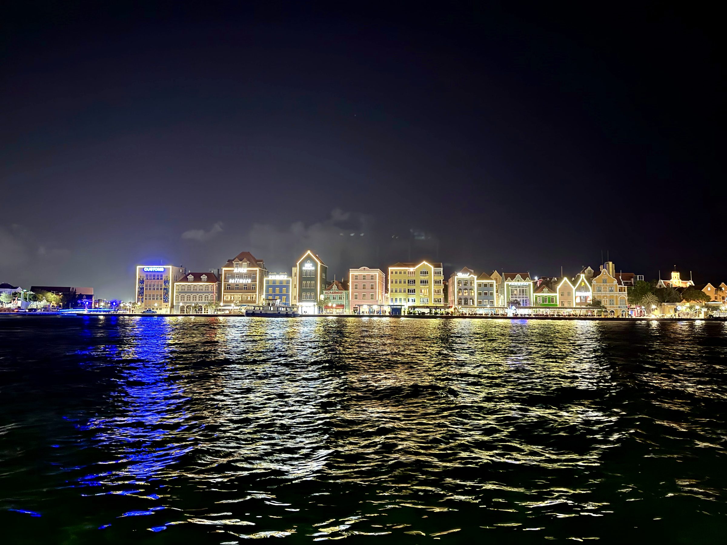 Handelskade waterfront in Willemstad lit up at night, reflected in the water